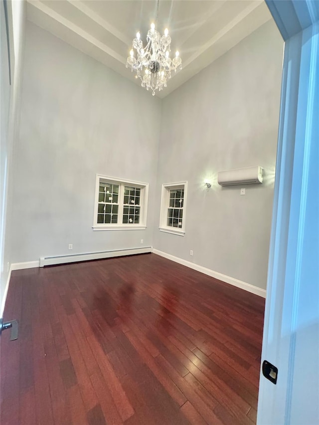 empty room with a baseboard heating unit, a chandelier, a wall mounted AC, and dark hardwood / wood-style floors