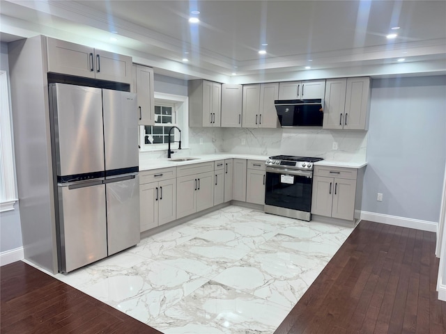 kitchen with gray cabinets, stainless steel appliances, backsplash, range hood, and sink