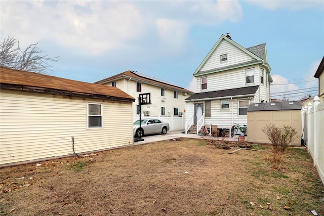 rear view of property with a lawn, a shed, and a patio area