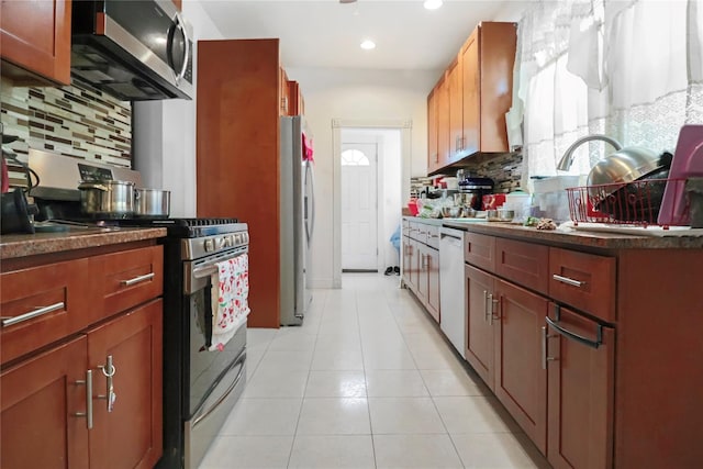 kitchen featuring light tile patterned flooring, stainless steel appliances, and decorative backsplash