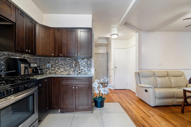 kitchen featuring stainless steel gas range oven, decorative backsplash, dark brown cabinets, and sink