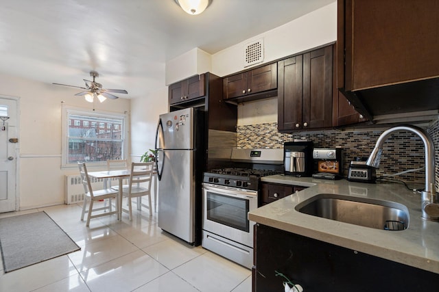 kitchen featuring stainless steel appliances, decorative backsplash, sink, light tile patterned flooring, and ceiling fan