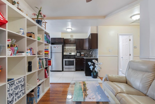 kitchen featuring decorative backsplash, sink, dark brown cabinetry, appliances with stainless steel finishes, and light tile patterned floors