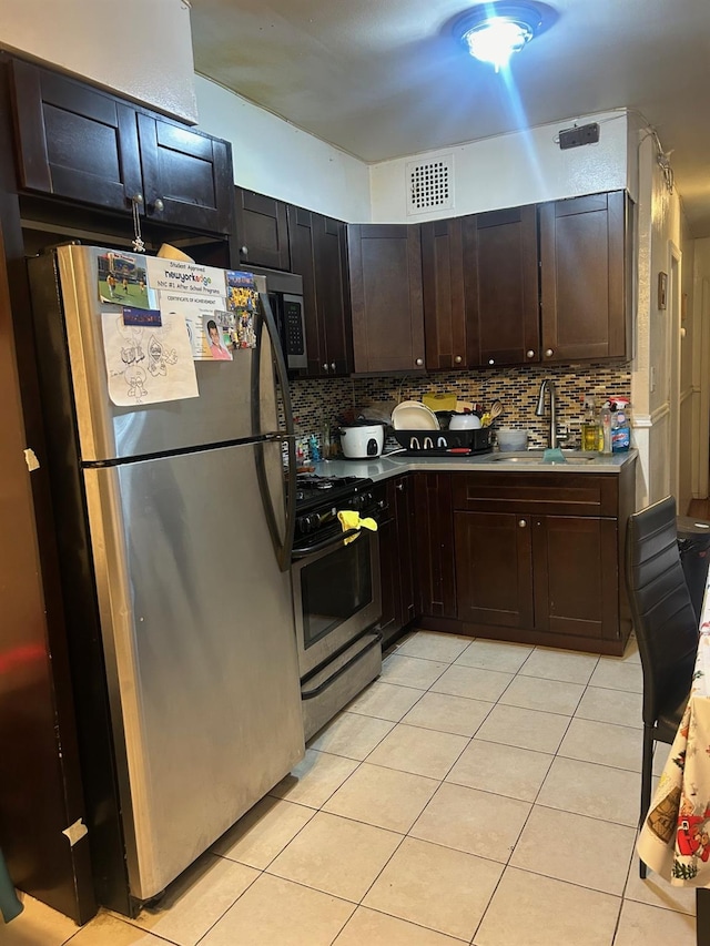 kitchen with tasteful backsplash, sink, light tile patterned flooring, dark brown cabinetry, and appliances with stainless steel finishes