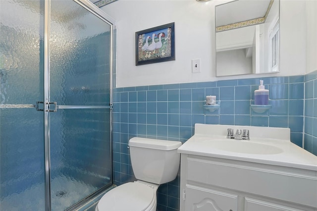 bathroom featuring tile walls, toilet, vanity, and a shower with shower door