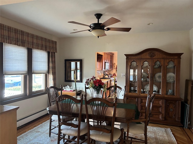 dining area with ceiling fan, hardwood / wood-style floors, and a baseboard heating unit