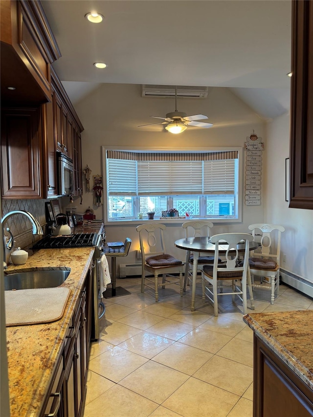 kitchen with sink, light tile patterned floors, light stone countertops, and appliances with stainless steel finishes