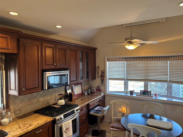 kitchen featuring light tile patterned flooring, appliances with stainless steel finishes, tasteful backsplash, ceiling fan, and light stone counters