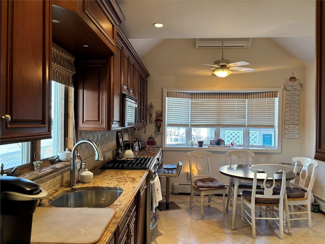 kitchen with sink, light tile patterned floors, appliances with stainless steel finishes, a wall unit AC, and light stone countertops