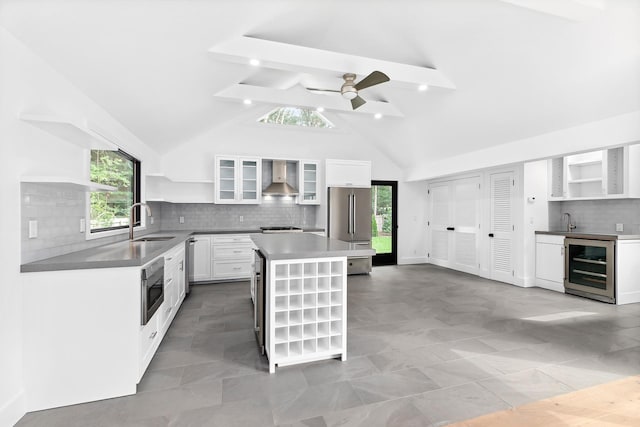 kitchen with beam ceiling, wall chimney range hood, white cabinetry, and a kitchen island