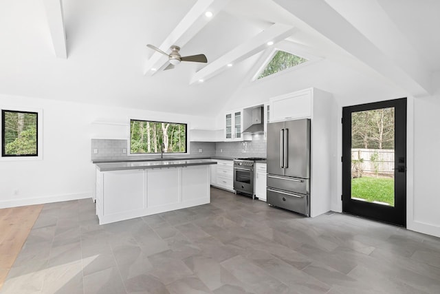 kitchen with ceiling fan, wall chimney exhaust hood, high quality appliances, white cabinets, and beamed ceiling