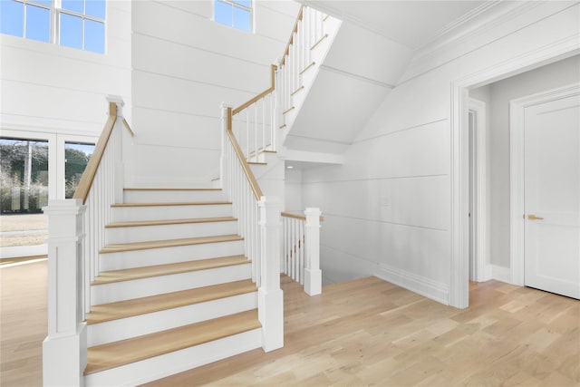 staircase with crown molding and wood-type flooring