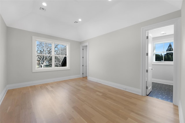 unfurnished room with vaulted ceiling and light wood-type flooring