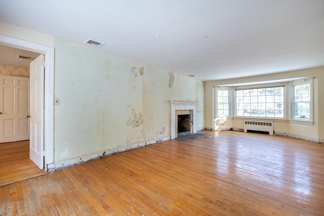 unfurnished living room featuring radiator heating unit and light hardwood / wood-style flooring