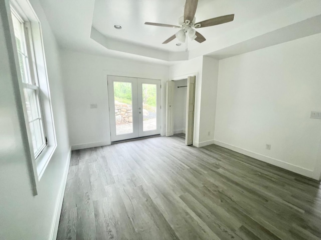 spare room with french doors, ceiling fan, a raised ceiling, and dark wood-type flooring