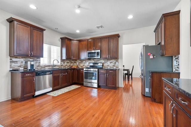 kitchen featuring light hardwood / wood-style floors, appliances with stainless steel finishes, and tasteful backsplash