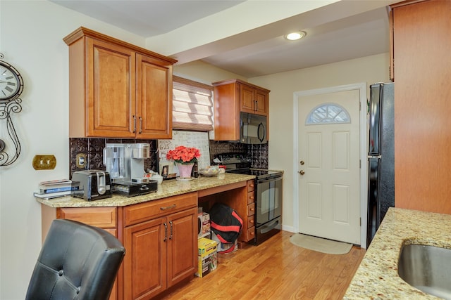 kitchen with light hardwood / wood-style flooring, backsplash, light stone counters, and black appliances