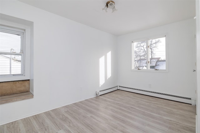 spare room with a baseboard radiator, light hardwood / wood-style floors, and a healthy amount of sunlight