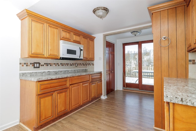 kitchen featuring light stone counters, light hardwood / wood-style floors, french doors, and backsplash