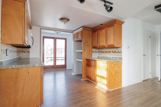 kitchen featuring backsplash, light hardwood / wood-style floors, and french doors