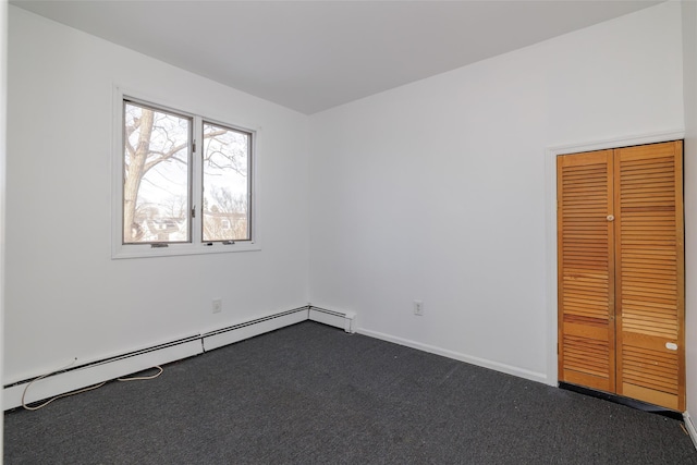 unfurnished room with dark carpet and a baseboard heating unit