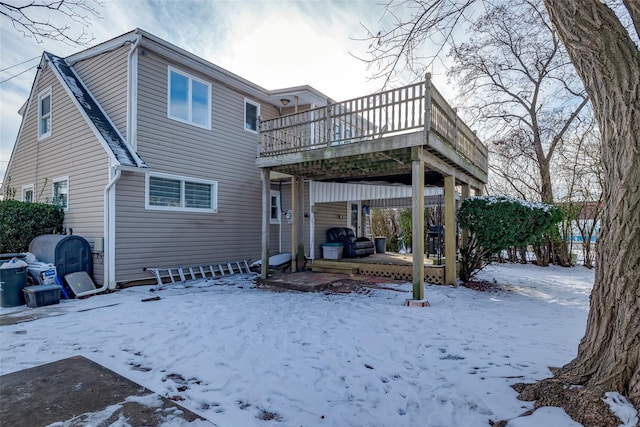 snow covered back of property featuring a wooden deck