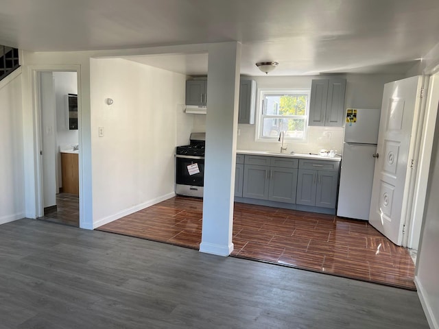 kitchen featuring dark hardwood / wood-style floors, white fridge, sink, stainless steel range with gas stovetop, and gray cabinetry