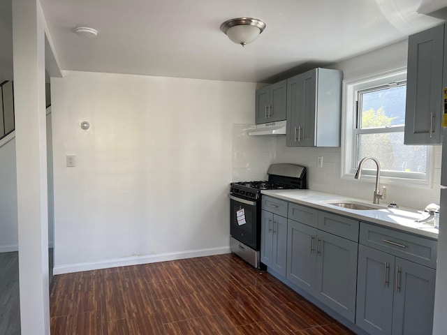 kitchen featuring gray cabinetry, decorative backsplash, stainless steel range with gas stovetop, and sink