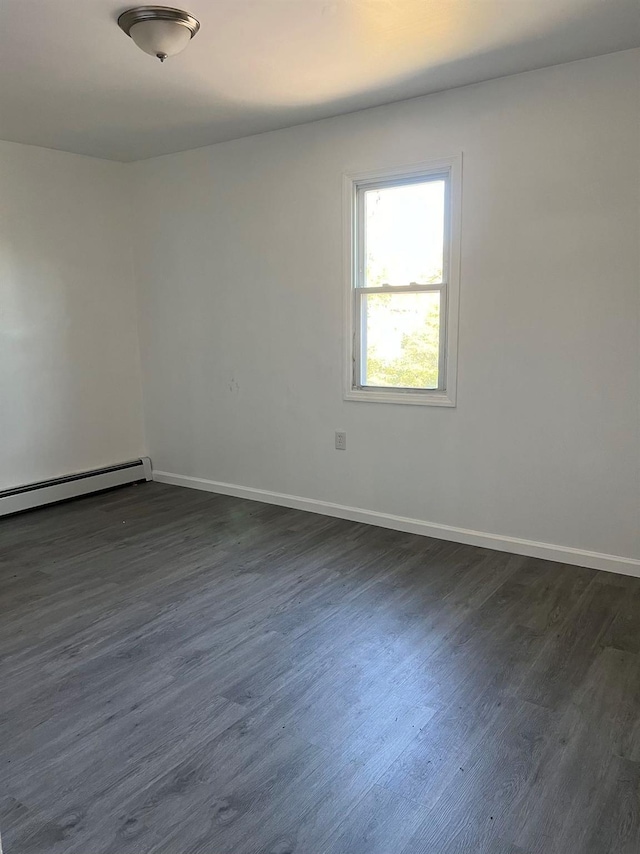 empty room featuring dark wood-type flooring and a baseboard radiator