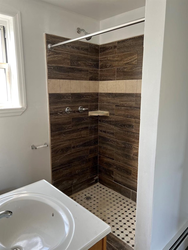 bathroom with tiled shower and vanity