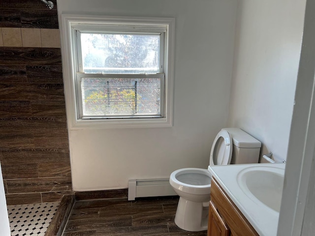 bathroom with a baseboard heating unit, toilet, a shower, and vanity