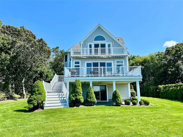 rear view of property featuring a balcony and a yard