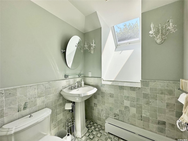 bathroom featuring tile patterned flooring, a baseboard heating unit, tile walls, sink, and toilet