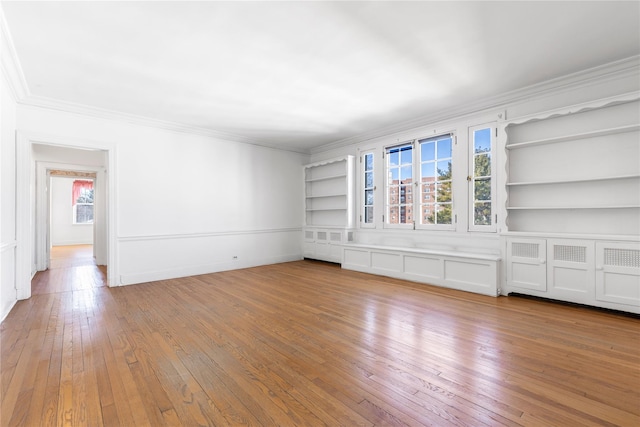 unfurnished living room featuring ornamental molding, light wood-type flooring, and built in shelves