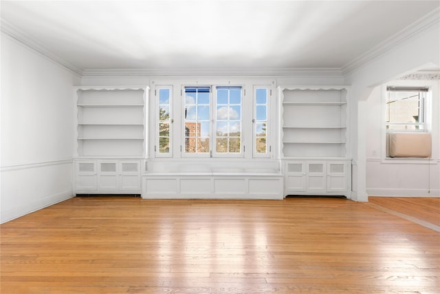 unfurnished living room with ornamental molding, a healthy amount of sunlight, light wood-type flooring, and built in shelves