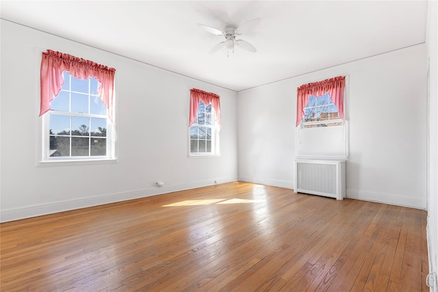 unfurnished room featuring hardwood / wood-style flooring, radiator heating unit, and ceiling fan