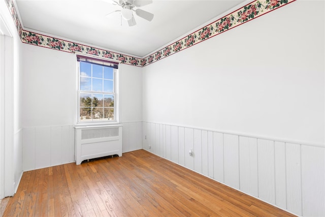 spare room featuring wood-type flooring, radiator, and ceiling fan