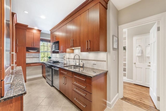 kitchen with dark stone countertops, decorative backsplash, light tile patterned flooring, sink, and range