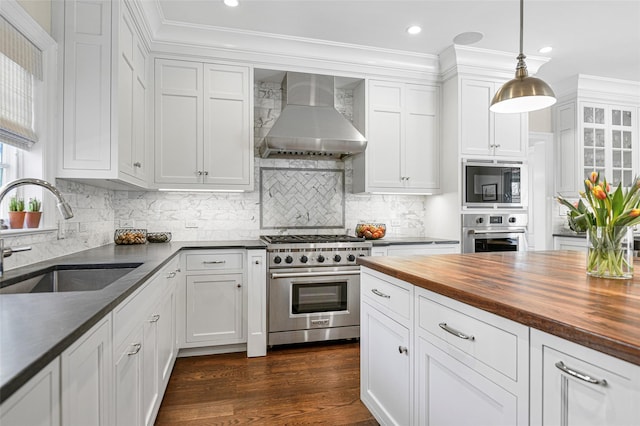 kitchen with butcher block countertops, a sink, stainless steel appliances, wall chimney exhaust hood, and white cabinets