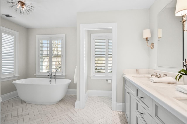 bathroom featuring a freestanding tub, baseboards, and a sink