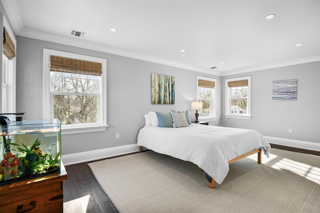 bedroom featuring visible vents, wood finished floors, baseboards, and ornamental molding