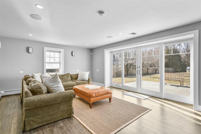 living room with recessed lighting, visible vents, baseboards, and wood finished floors