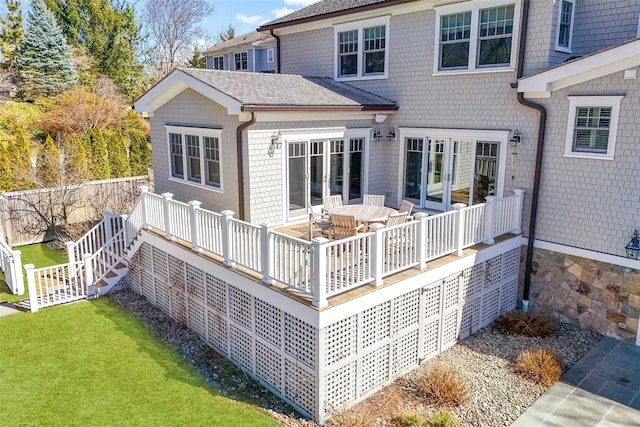 rear view of house featuring a shingled roof, a yard, and a wooden deck