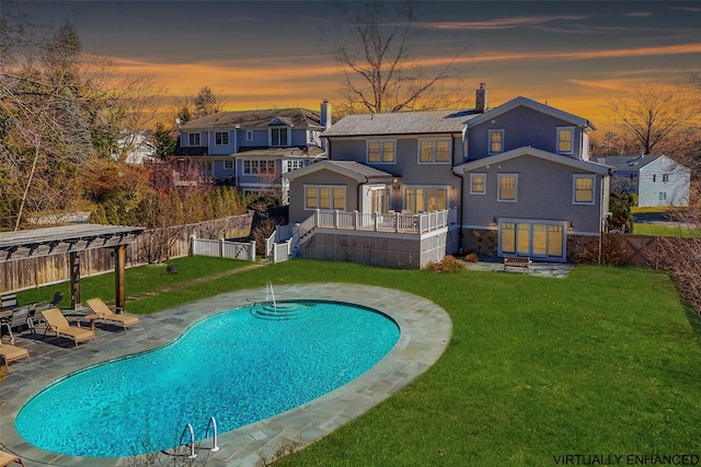 rear view of property featuring a fenced in pool, a lawn, a chimney, a fenced backyard, and a patio area