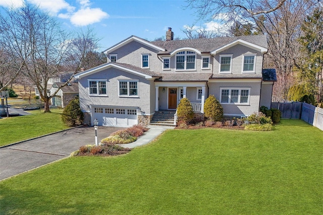 view of front of property featuring fence, a chimney, a front lawn, a garage, and aphalt driveway