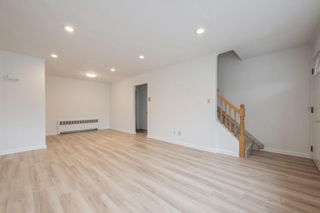 empty room with light wood-type flooring and radiator heating unit