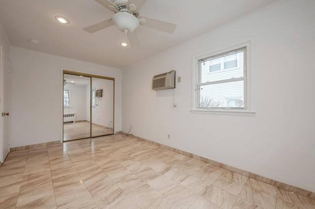 unfurnished bedroom featuring ceiling fan, a wall mounted air conditioner, a closet, radiator, and multiple windows