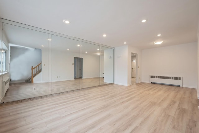 spare room featuring radiator and light wood-type flooring