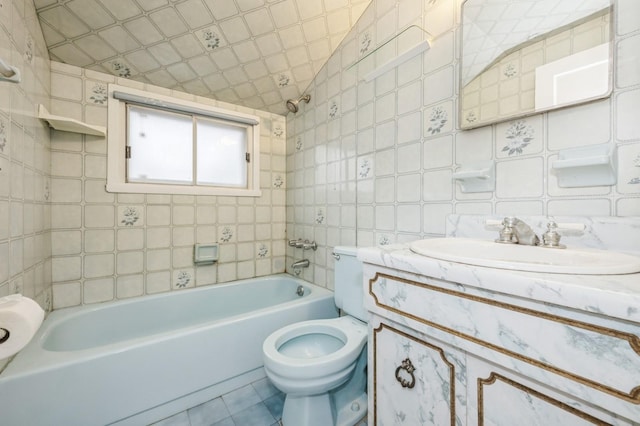 full bathroom featuring toilet, tiled shower / bath, tile walls, tile patterned floors, and vanity