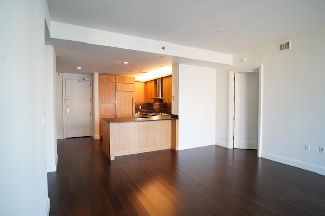 kitchen featuring sink, paneled built in refrigerator, dark hardwood / wood-style floors, kitchen peninsula, and backsplash